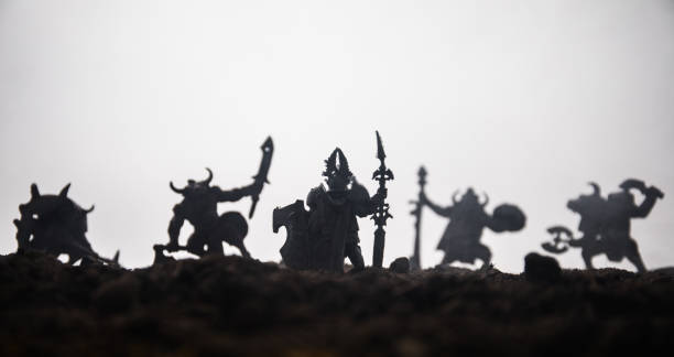 istock Medieval battle scene with cavalry and infantry. Silhouettes of figures as separate objects, fight between warriors on sunset foggy background. Selective focus 1130283901