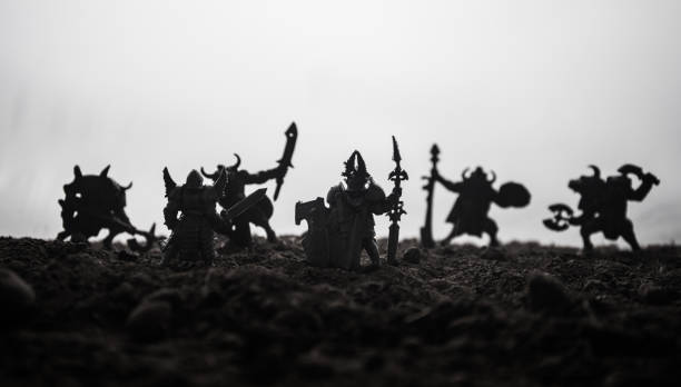 istock Medieval battle scene with cavalry and infantry. Silhouettes of figures as separate objects, fight between warriors on sunset foggy background. Selective focus 1130283909