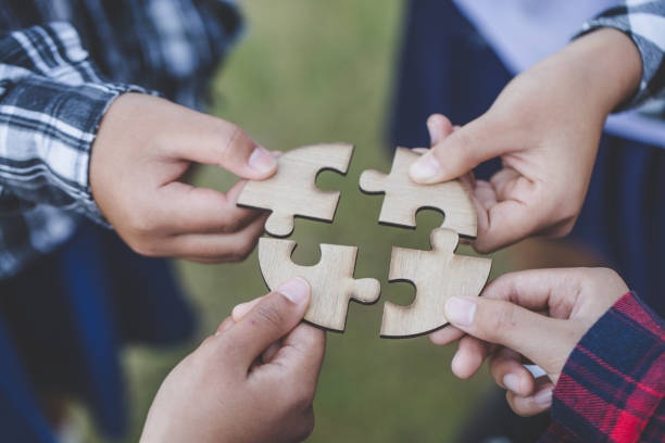 パズルの組み立てを手伝っている人、意思決定の協力、問題解決のチームサポート、グループワークのコンセプト、手をつなぐ部分を間近に見る - human hand puzzle togetherness connection ストックフォトと画像