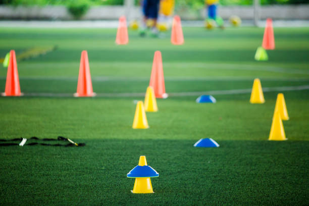 istock Cone markers is soccer training equipment on green artificial turf with blurry kid players training background 1130288038