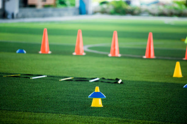 istock Cone markers is soccer training equipment on green artificial turf with blurry kid players training background 1130288046