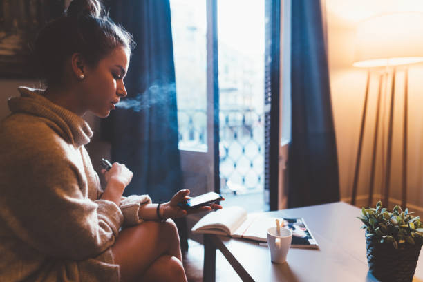 istock Cute girl in Barcelona smoking e-cigarette and using smartphone 1130289681