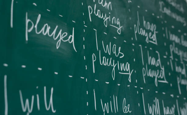 Hand writing on a chalkboard in an language english class. Hand writing on a chalkboard in an language english class verb stock pictures, royalty-free photos & images
