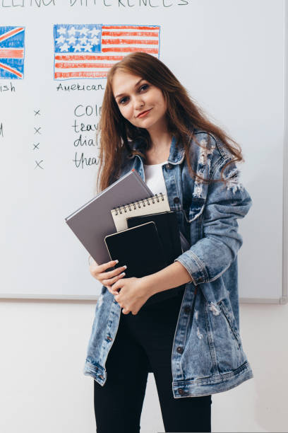 istock Female student with books in classroom English language school. 1130293558
