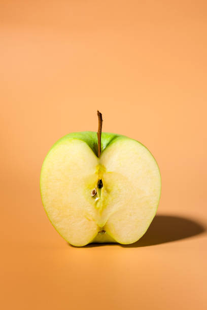 istock Sliced green delicious apple isolated on orange background, contrast shadows 1130297808