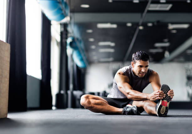 Young man doing leg stretches in the gym stock photo