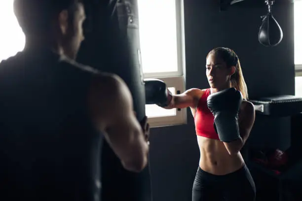 Young woman box training in the gym with trainer.