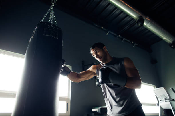 Concentrated young man box training in the gym Concentrated young man box training by himself in the gym. kickboxing stock pictures, royalty-free photos & images