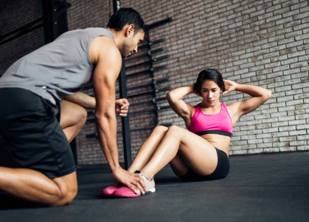 istock Young fitness trainer with a young woman doing core exercise 1130300429