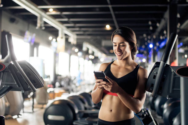 istock Young latin woman texting in the gym 1130300461