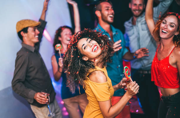 felizes amigos fazendo a festa na boate lifestyle de feriados, amizade, vida noturna e jovens - jovem se divertindo com seu grupo de companheiros de comer doces pirulitos dentro disco- - clube noturno - fotografias e filmes do acervo