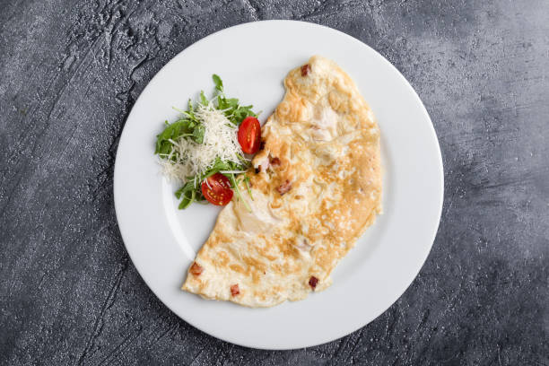 filled omelette with cheese and tomato on white plate stock photo
