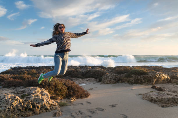istock girl jumping on the beach at sunset 1130304870