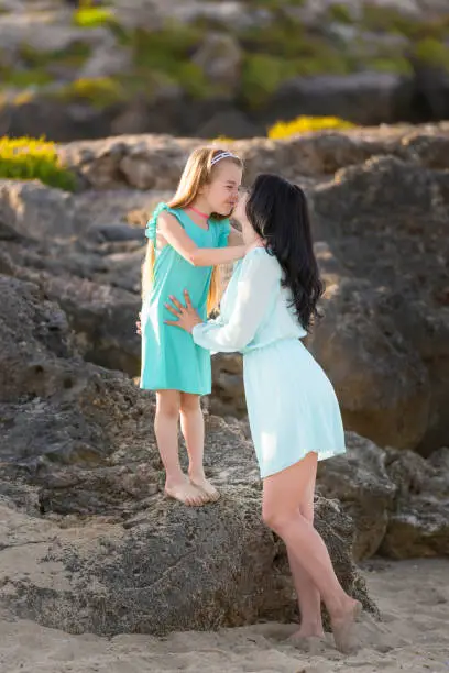 Photo of happy family at the beach. motherand child daughter hug at sunset