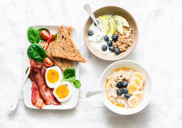 istock Varied sweet and savory breakfast - bacon with egg and vegetables, spinach salad, yogurt with granola and fruit, vegetarian oatmeal on a light background, top view 1130307501