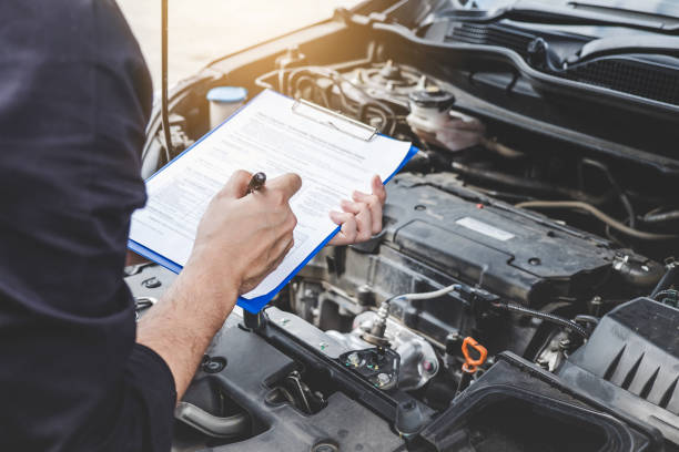 servizi concetto di macchina motore auto, riparatore meccanico automobilistico che controlla un motore dell'auto con ispezione scrivendo negli appunti la lista di controllo per macchina di riparazione, assistenza auto e manutenzione - car examining mechanic auto mechanic foto e immagini stock