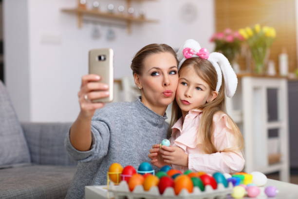 istock Mother and daughter painting Easter eggs and taking selfie 1130309101