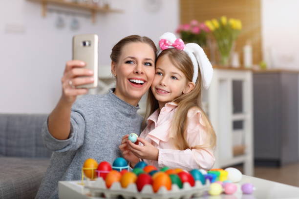 mother and daughter painting easter eggs and taking selfie - egg cell imagens e fotografias de stock