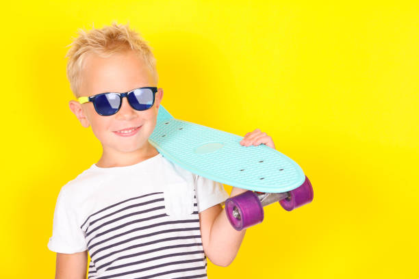 istock Cute cool blond boy wearing sunglasses with skateboard in his arms 1130309384