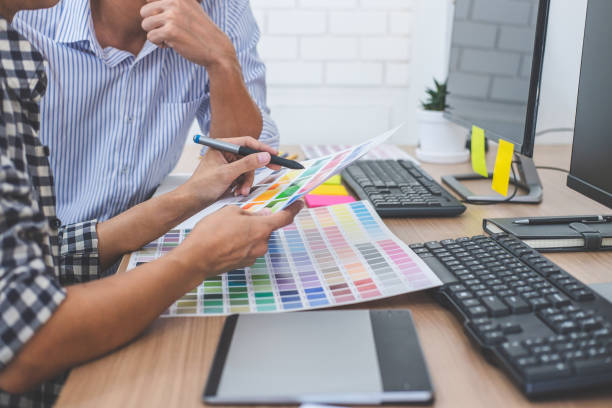 istock Two colleagues creative graphic designer working on color selection and drawing on graphics tablet at workplace, Color swatch samples chart for selection coloring 1130310313