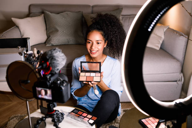 Female vlogger showing cosmetic accessories while recording content stock photo