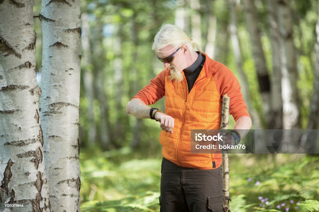 Junger Mann mit Bart in der Natur steht, wenn er auf eine Uhr schaut - Lizenzfrei Abenteuer Stock-Foto