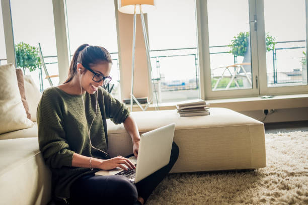istock cheerful young woman using laptop at home 1130311975