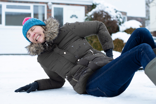 Mujer en el dolor cayendo en la nieve en la calle resbaladiza y lesionarse a sí misma photo