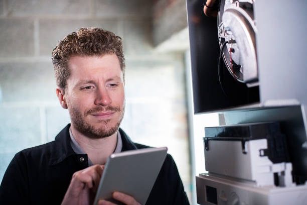 dijital tablet kullanarak merkezi isıtma kazanı üzerinde çalışan erkek isıtma mühendisi - isıtma tesisatı mühendisi stok fotoğraflar ve resimler