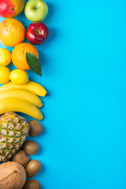 istock Different tropical and seasonal summer fruit arranged in side border. Pineapple mango coconut oranges lemons apples kiwi bananas on light blue background. Healthy lifestyle vitamins vegan 1130318749
