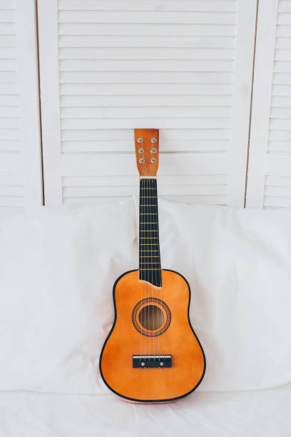 istock Guitar lies on a white bed. Romantic composition. 1130321197