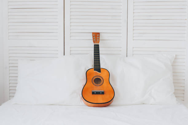 istock Guitar lies on a white bed. Romantic composition. 1130321217