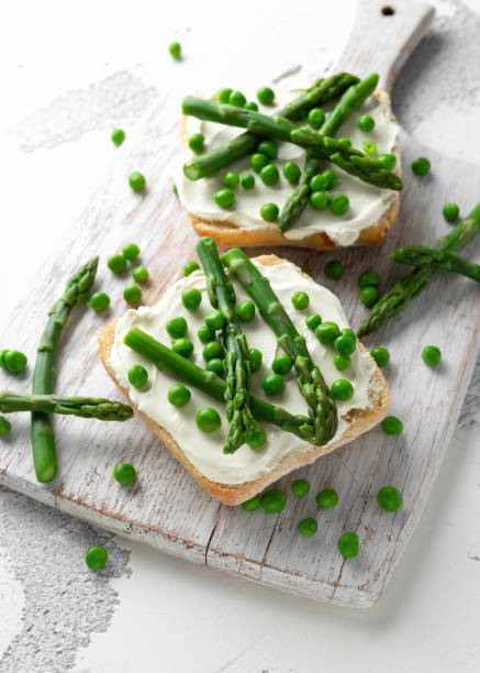 istock Appetizer bruschetta, toast with Asparagus, Peas and creamy soft cheese. on white board. 1130325840