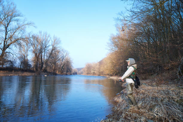 istock A woman catches a spinning fish while standing on a riverbank 1130328862