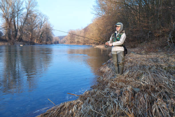 istock A woman catches a spinning fish while standing on a riverbank 1130328866