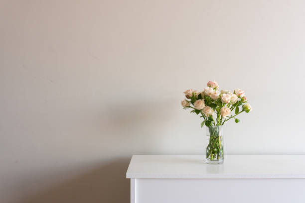 istock Pale pink roses in glass vase on sideboard with copy space 1130332064