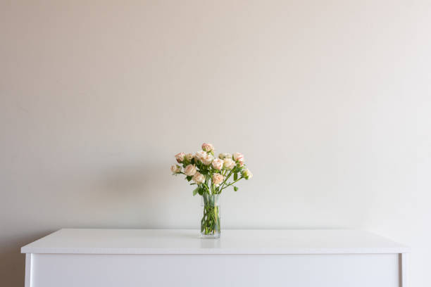 istock Pale pink roses in glass vase on sideboard 1130332275