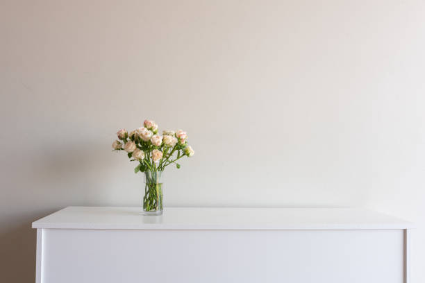 istock Pale pink roses in glass vase on sideboard 1130332502