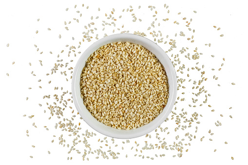 Sesame seeds in a bowl on white background shot directly from above