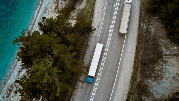 air view of the road by the sea with trucks - grass area field air sky imagens e fotografias de stock