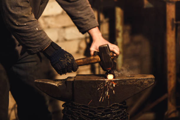 istock The blacksmith manually forging the red-hot metal on the anvil in smithy with spark fireworks. 1130338655