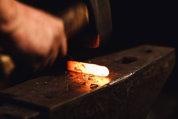 istock blacksmith makes an artistic forging of hot metal on the anvil. 1130338675