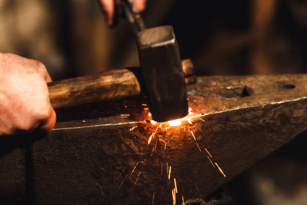 istock The blacksmith manually forging the red-hot metal on the anvil in smithy with spark fireworks. 1130338679
