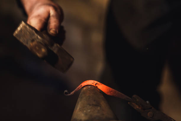 istock blacksmith makes an artistic forging of hot metal on the anvil. 1130338698