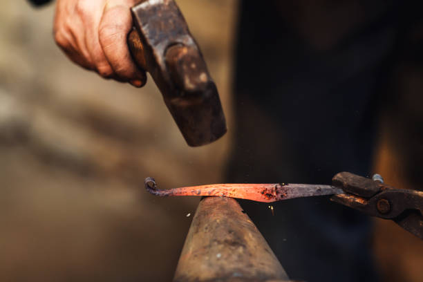 istock blacksmith makes an artistic forging of hot metal on the anvil. 1130338701