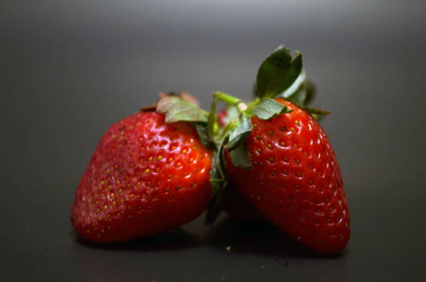 three strawberries three strawberries on black background tres objetos stock pictures, royalty-free photos & images