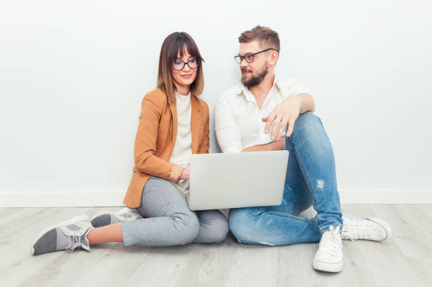istock Two young coworkers dressed casual using laptop in white interior 1130344351