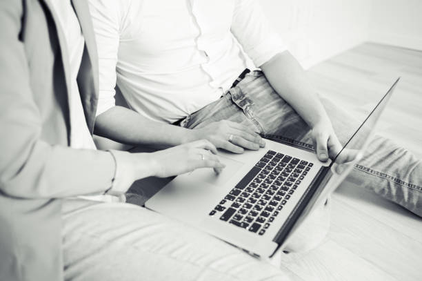 istock Two young coworkers dressed casual using laptop in white interior 1130345139