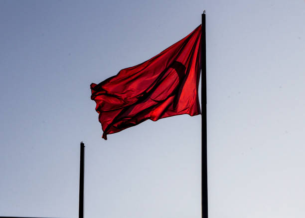 istock Levent, Istanbul / Turkey - February 17th, 2019: Turkish flag on pole streaming under evening sun with clear sky background and another empty pole. 1130346898