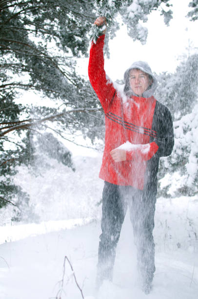 istock young man in a red sweater showering snow from pine branches in the forest 1130348360